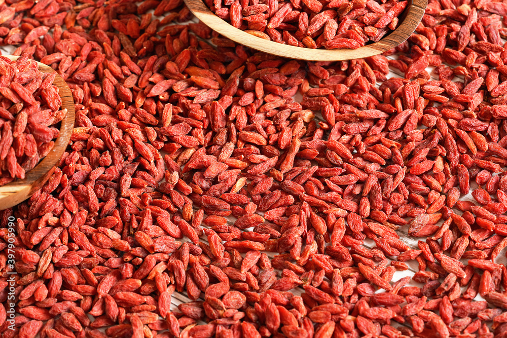 Fototapeta premium Dry goji berries in small wooden bowls, scattered on desk below