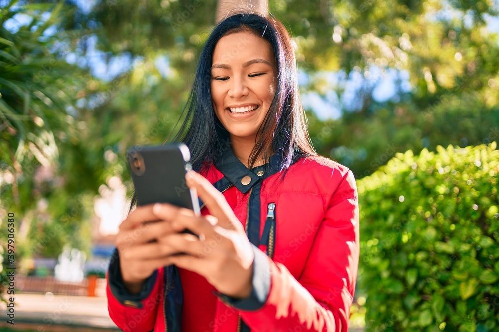 Young latin woman smiling happy using smartphone at the park. Young latin woman smiling happy using smartphone at the park.