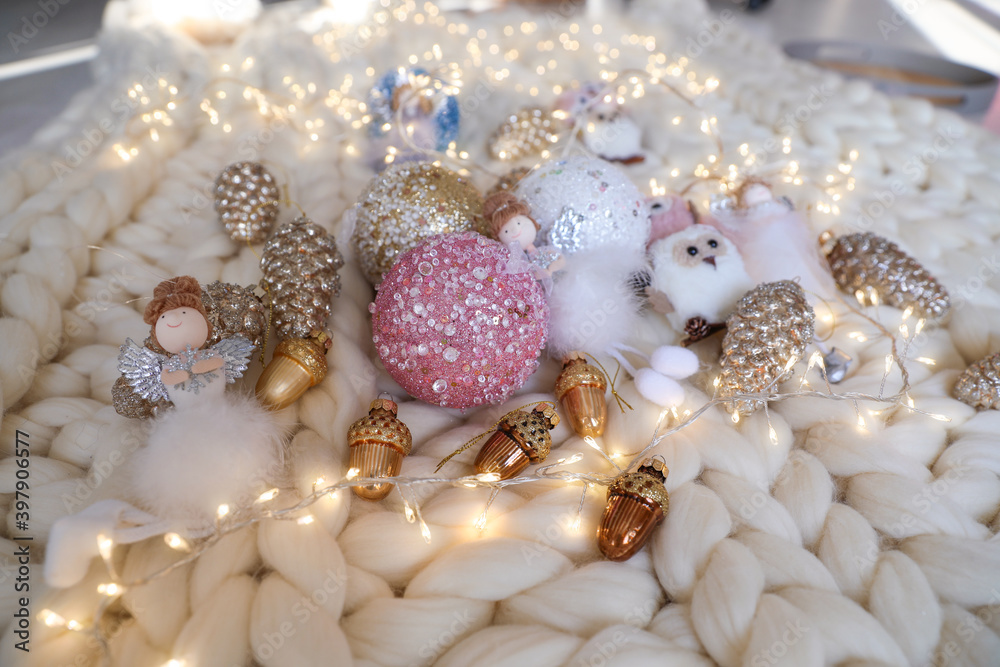 Beautiful Christmas tree baubles, toys and fairy lights on white knitted fabric Beautiful Christmas tree baubles, toys and fairy lights on white knitted fabric