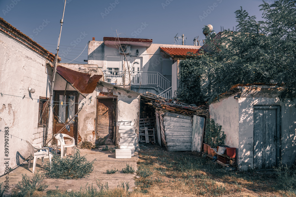Abandoned and half ruined traditional Greek house backyard exterior in Sarti sea coastal village with plastic chairs and many chambers Abandoned and half ruined traditional Greek house backyard exterior in Sarti sea coastal village with plastic chairs and many chambers