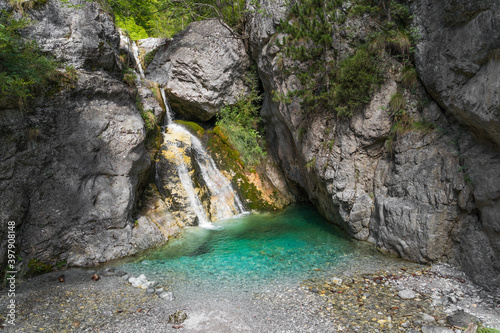 Beautiful and hidden secret waterfall on Olympus mountain in the Northern Greece with amazing crystal clear and blue green cold water lit with a sun in summer 