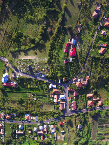 Aerial top view of a rural village in Romania. An road intersection, the church and the surrounding hill can be seen in this image.