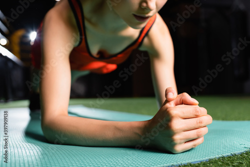 partial view of sportswoman doing plank exercise while training in gym, blurred background