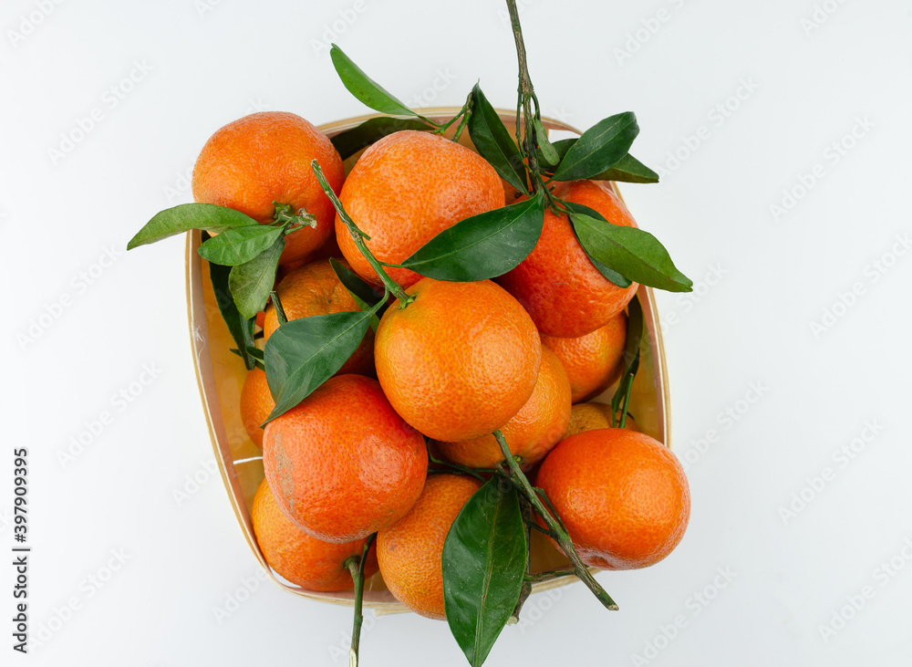 Extra sweet and juicy Spanish clementines with leaves in a basket. Isolated on white. Top down view. Extra sweet and juicy Spanish clementines with leaves in a basket. Isolated on white. Top down view.