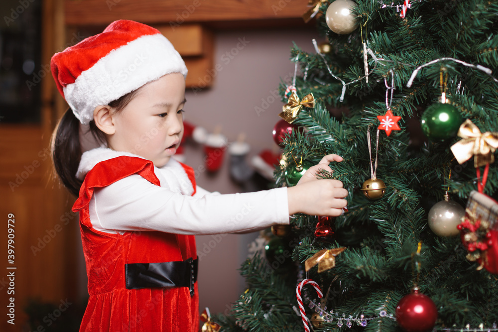 young girl decorating Christmas tree at home