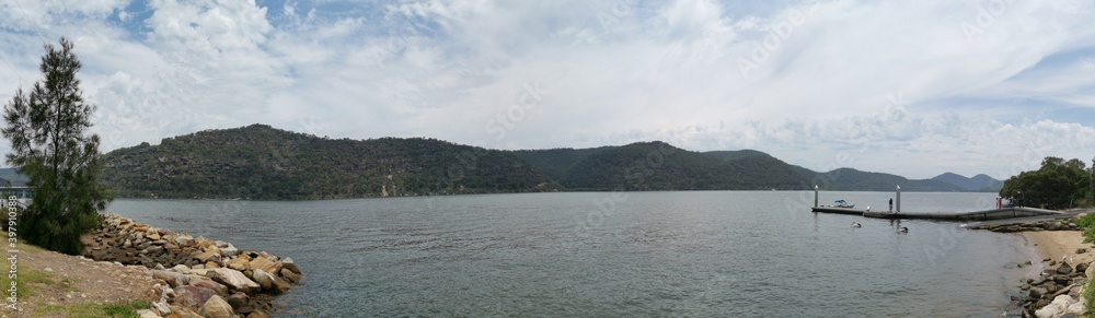 Beautiful panoramic view of a river on a cloudy day with tall mountains and trees in the background, Hawkesbury river, Deerubbun Reserve, Mooney Mooney, New South Wales, Australia
