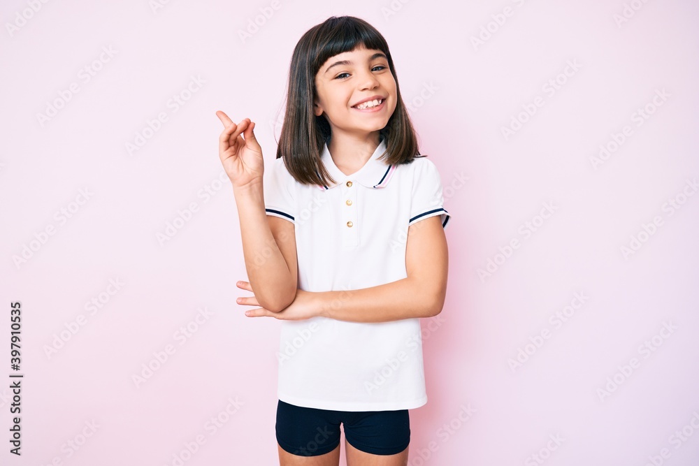 Young little girl with bang wearing sportswear smiling happy pointing with hand and finger to the side Young little girl with bang wearing sportswear smiling happy pointing with hand and finger to the side