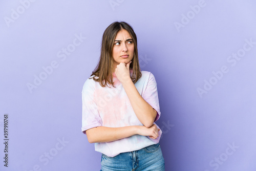 Young caucasian woman looking sideways with doubtful and skeptical expression.