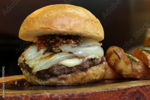 Hamburger. Made on the barbecue grill. With cheese, bacon, onion, pickle. On wooden background