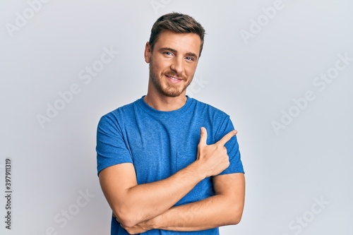 Handsome caucasian man wearing casual clothes smiling cheerful pointing with hand and finger up to the side