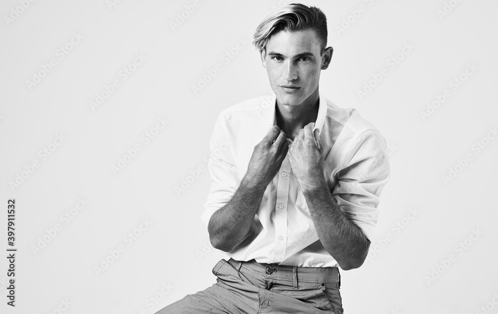 Fototapeta premium Black and white photograph of a handsome man gesturing with his hands on a light background cropped view