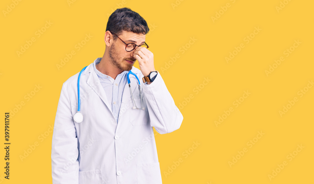 Handsome young man with bear wearing doctor uniform tired rubbing nose and eyes feeling fatigue and headache. stress and frustration concept. Handsome young man with bear wearing doctor uniform tired rubbing nose and eyes feeling fatigue and headache. stress and frustration concept.