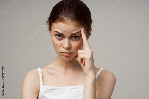 young woman touching her face with hands on a gray background health problems cosmetology acne care