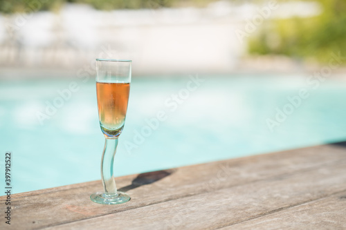Glass of rosé wine at the edge of a swimming pool