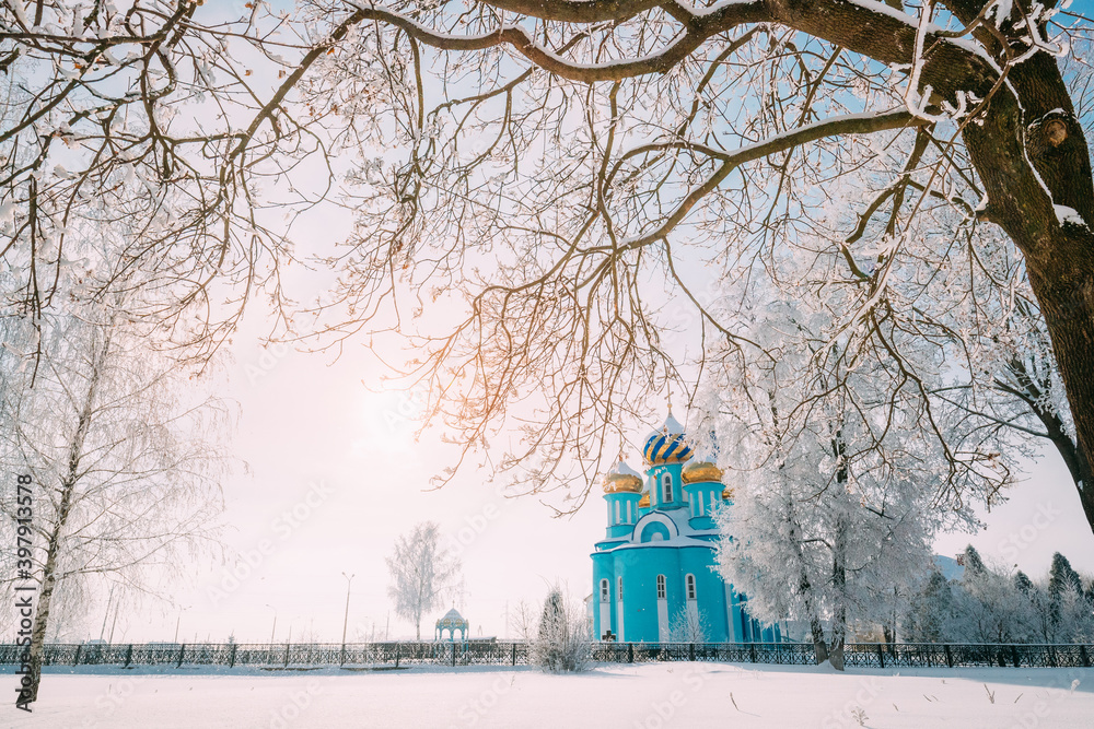 Village Krasnoe, Gomel Region, Belarus. Old Orthodox Church Of The Assumption At Sunny Winter Snowy Day. Famous Landmark In Snowy Park. Village Krasnoe, Gomel Region, Belarus. Old Orthodox Church Of The Assumption At Sunny Winter Snowy Day. Famous Landmark In Snowy Park.