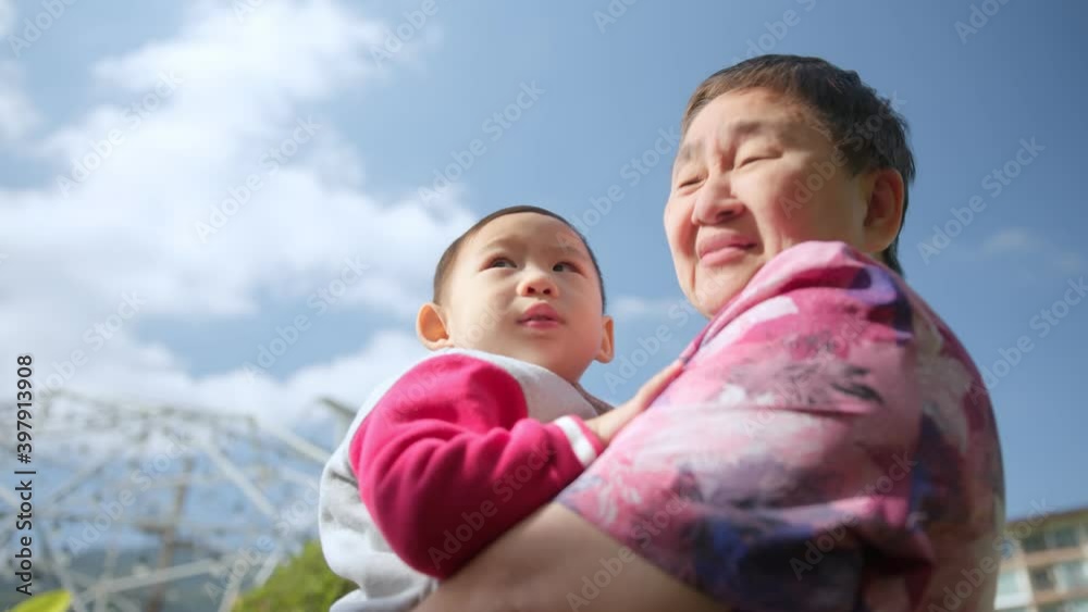Happy asian family.Grandmother plays with her young nephew in the Park at daytime, tossing the child in the air against the blue sky. Happy childhood.Family happiness generation cheerful lifestyle