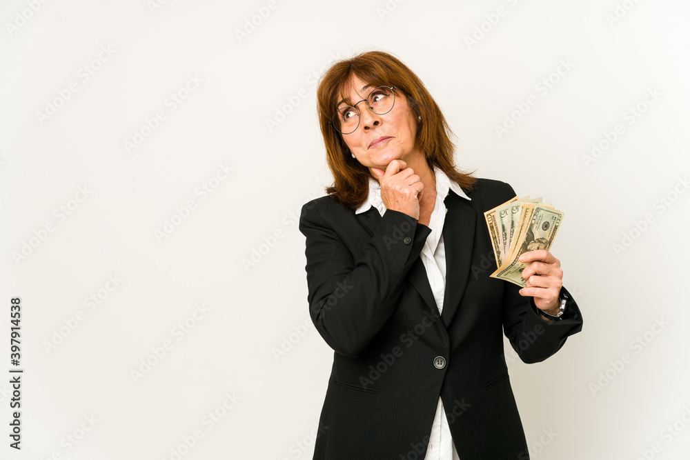 Middle age caucasian business woman holding banknotes isolated looking sideways with doubtful and skeptical expression. Middle age caucasian business woman holding banknotes isolated looking sideways with doubtful and skeptical expression.