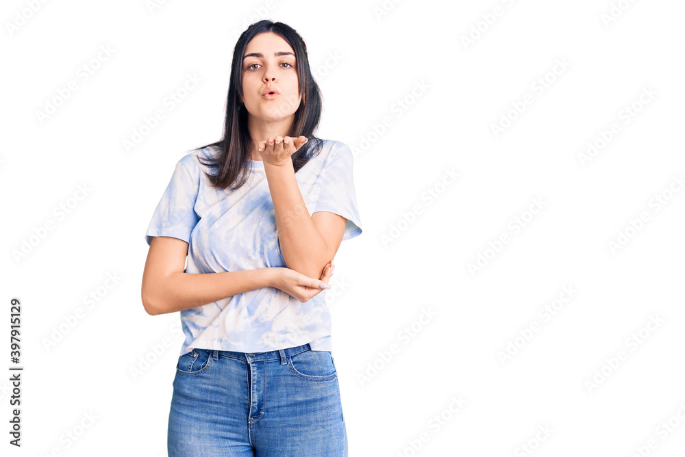 Young beautiful girl wearing casual t shirt looking at the camera blowing a kiss with hand on air being lovely and sexy. love expression. Young beautiful girl wearing casual t shirt looking at the camera blowing a kiss with hand on air being lovely and sexy. love expression.