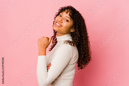 Young african american afro woman isolated points with thumb finger away, laughing and carefree.