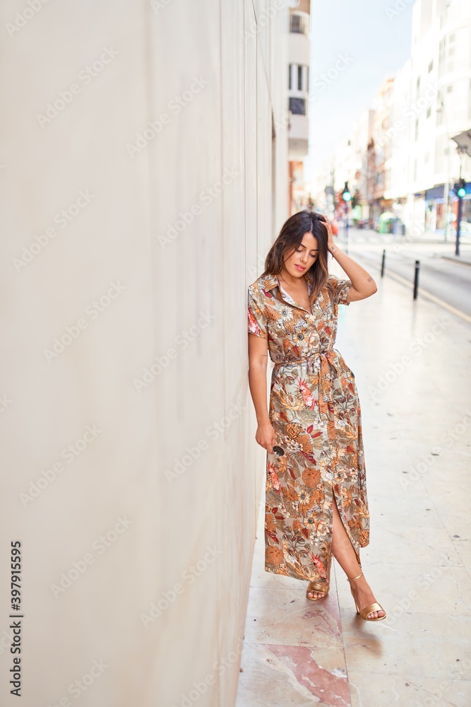 Fototapeta premium Beautiful young woman wearing fashionable clothes walking down the street
