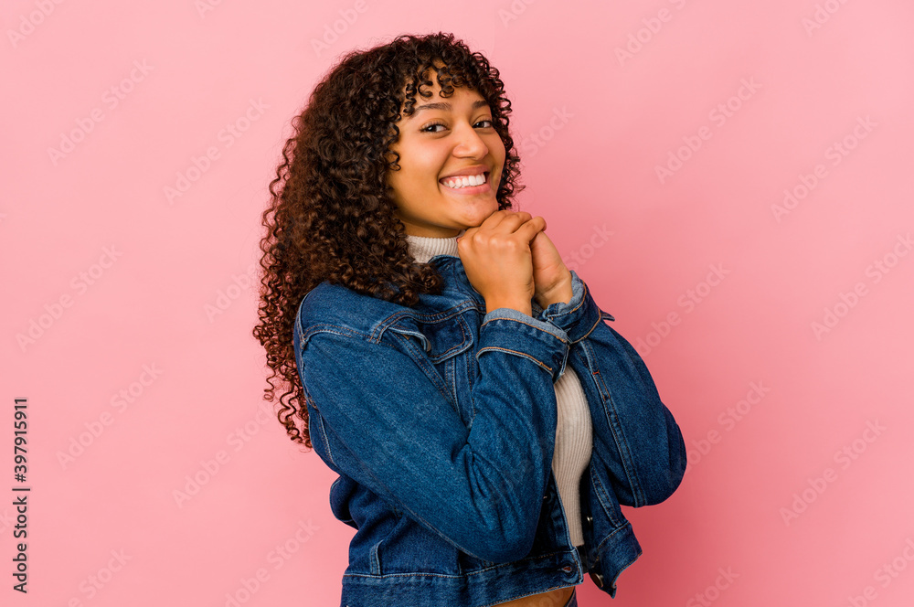Young african american afro woman isolated keeps hands under chin, is looking happily aside. Young african american afro woman isolated keeps hands under chin, is looking happily aside.