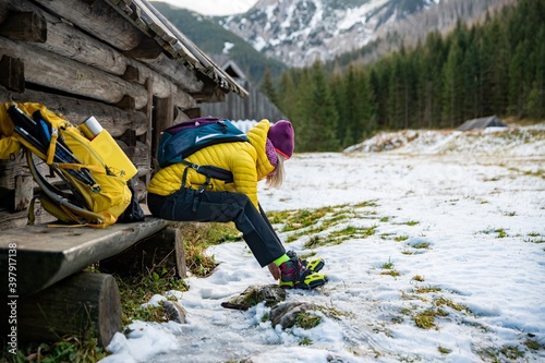 A female tourist in a yellow down jacket wears crampons before going to the top.