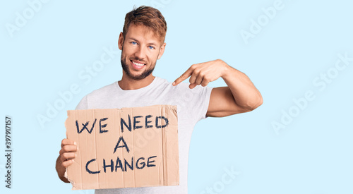 Young caucasian man holding we need a change banner pointing finger to one self smiling happy and proud