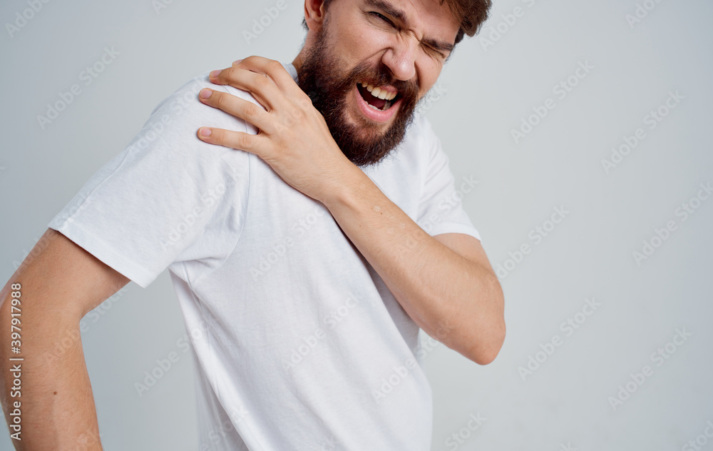 man touching shoulder with hand dislocation discomfort white t-shirt man touching shoulder with hand dislocation discomfort white t-shirt