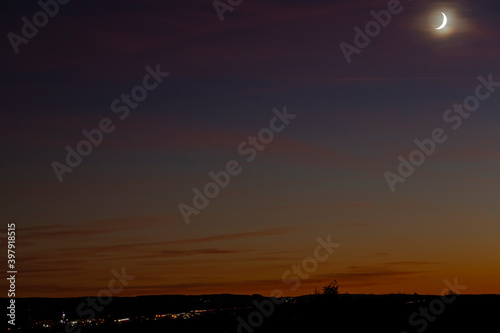 Waxing crescent moon in a beautiful dusk landscape during autumn season.