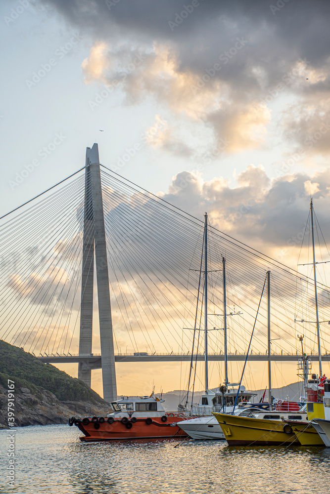 Obraz premium Panoramic view of the Yavuz Sultan Selim Bridge in Istanbul, Turkey. Sunset time. Small port with yachts and fishing boats in front of Third Istanbul bridge.