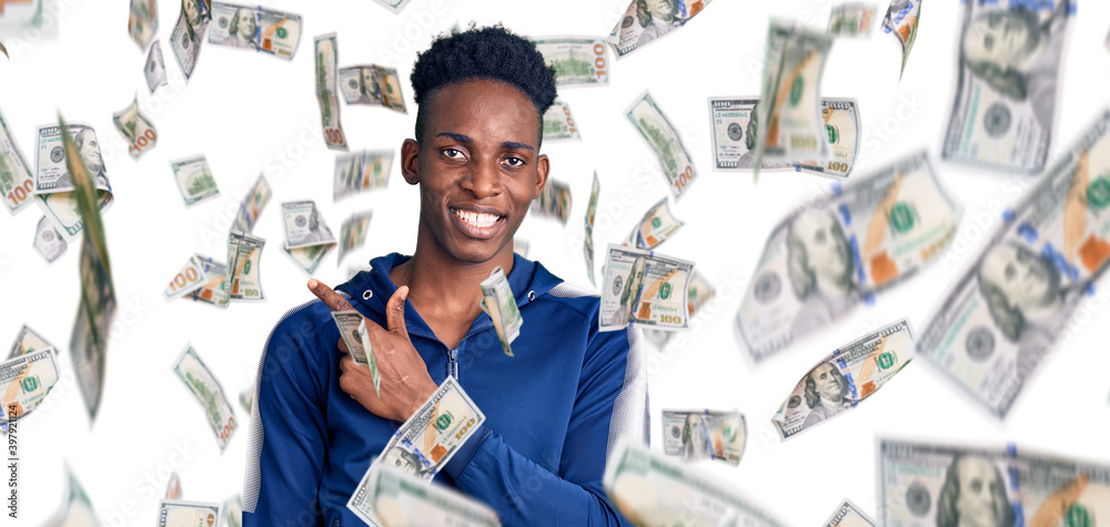 Young african american man wearing sportswear cheerful with a smile on face pointing with hand and finger up to the side with happy and natural expression Young african american man wearing sportswear cheerful with a smile on face pointing with hand and finger up to the side with happy and natural expression
