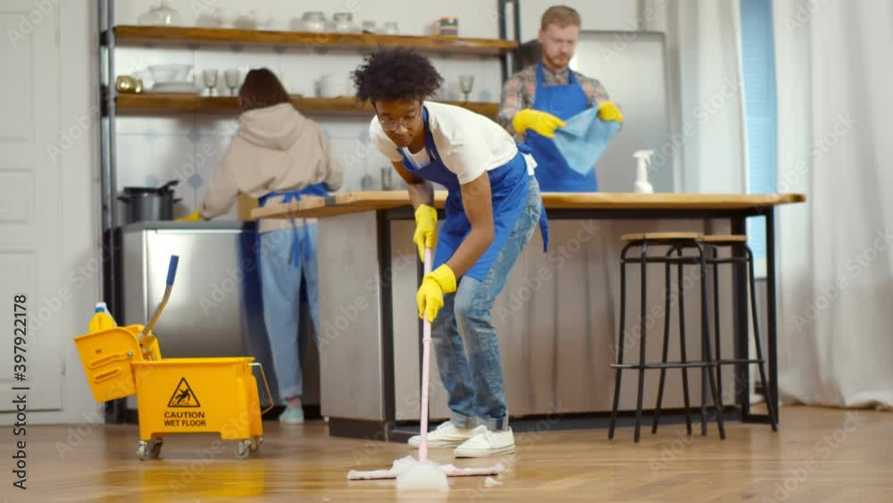 Young professional cleaners in uniform working together in kitchen.