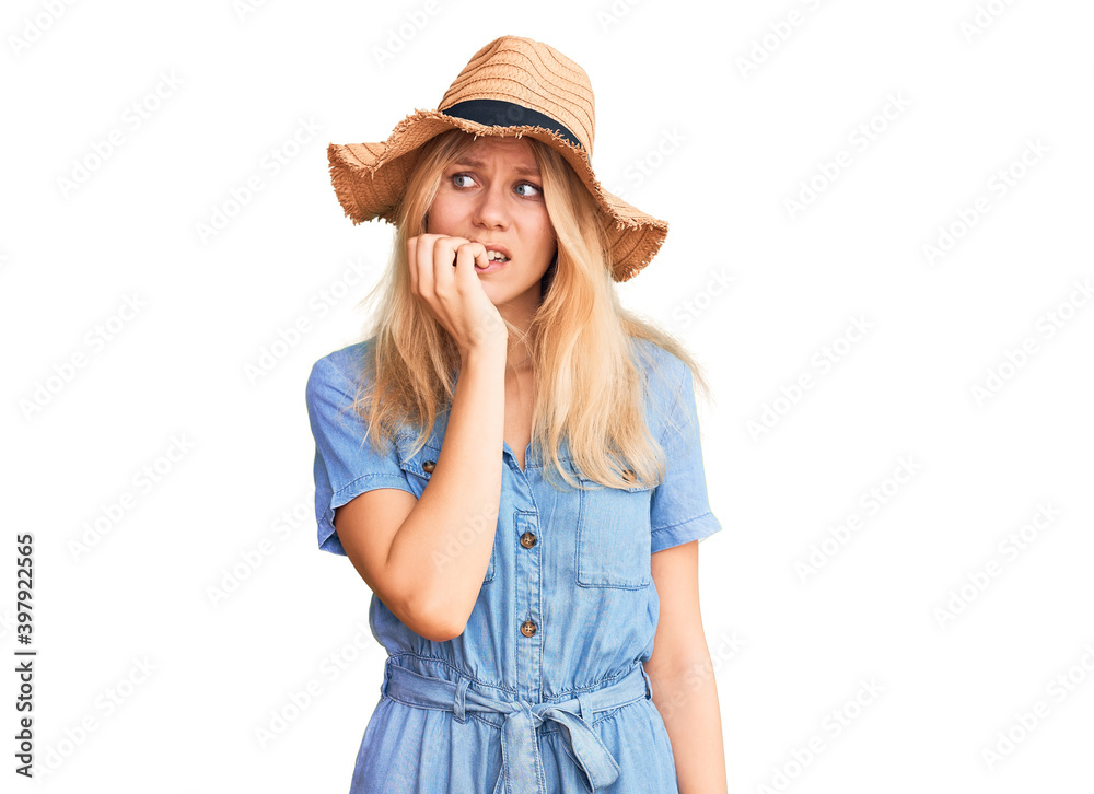 Young beautiful blonde woman wearing summer hat and dress looking stressed and nervous with hands on mouth biting nails. anxiety problem. Young beautiful blonde woman wearing summer hat and dress looking stressed and nervous with hands on mouth biting nails. anxiety problem.