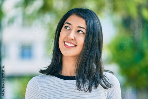 Young hispanic woman smiling happy walking at the park.
