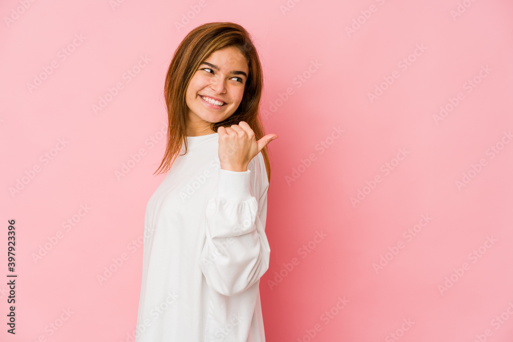 Young skinny caucasian teenager girl points with thumb finger away, laughing and carefree. Young skinny caucasian teenager girl points with thumb finger away, laughing and carefree.