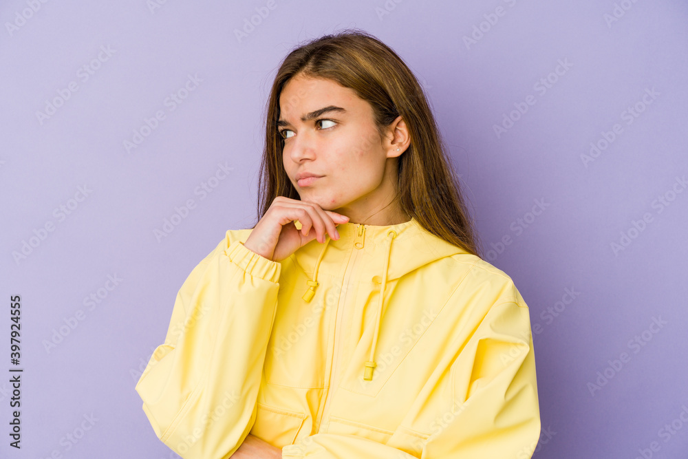 Young skinny caucasian girl teenager on purple background looking sideways with doubtful and skeptical expression. Young skinny caucasian girl teenager on purple background looking sideways with doubtful and skeptical expression.