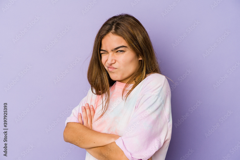 Young skinny caucasian girl teenager on purple background frowning face in displeasure, keeps arms folded. Young skinny caucasian girl teenager on purple background frowning face in displeasure, keeps arms folded.