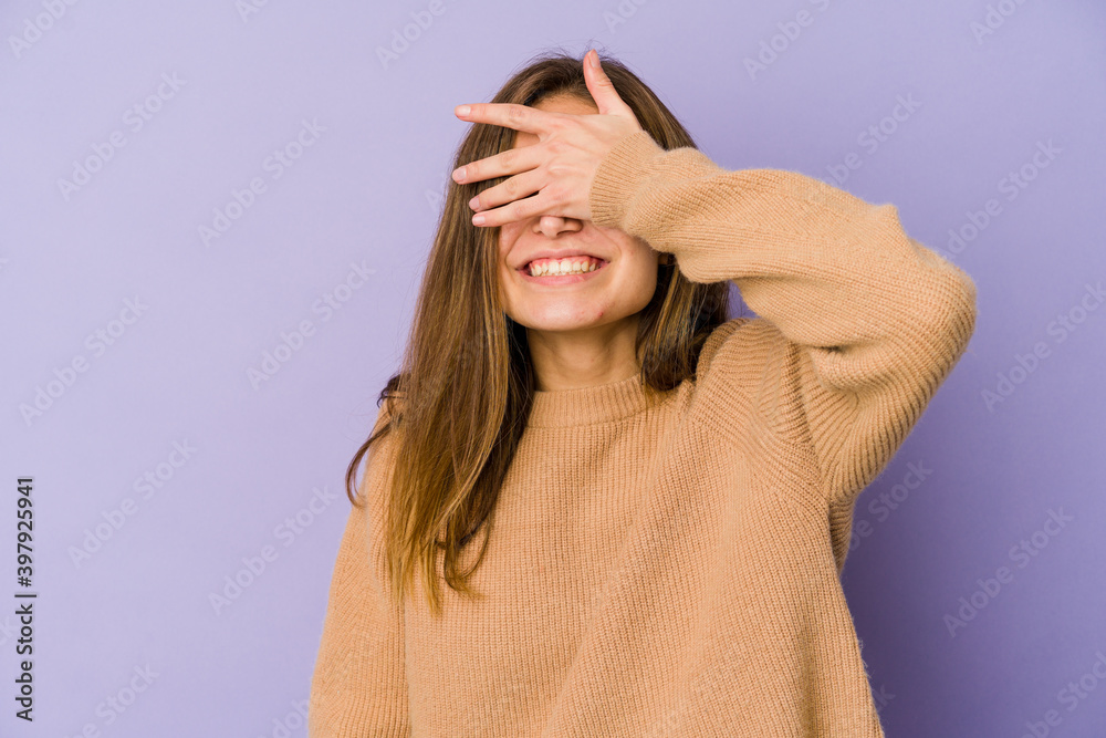 Young skinny caucasian girl teenager on purple background covers eyes with hands, smiles broadly waiting for a surprise. Young skinny caucasian girl teenager on purple background covers eyes with hands, smiles broadly waiting for a surprise.
