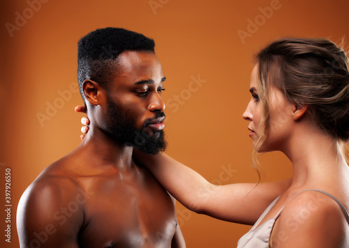 young pretty couple diverse races together posing sensitive on brown background, lifestyle people concept