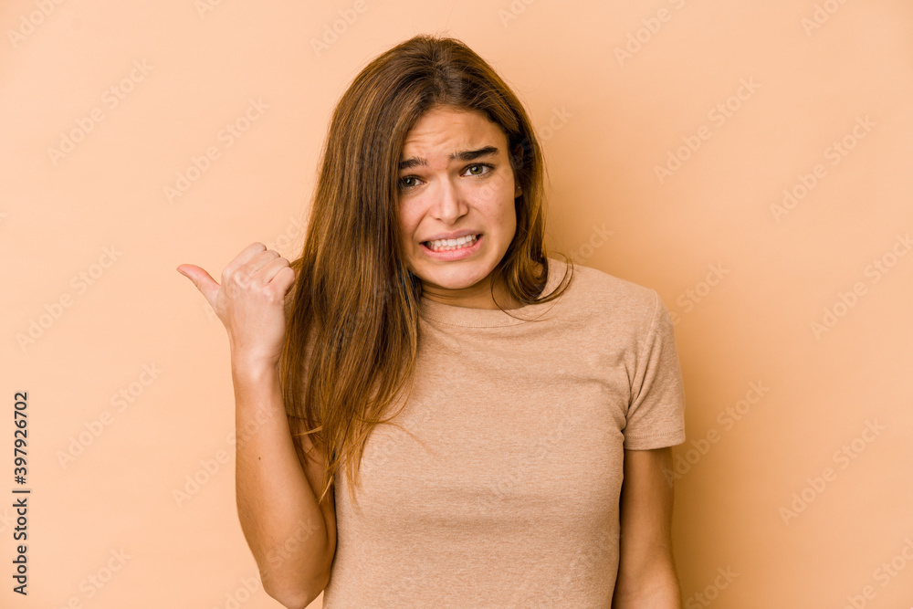 Young skinny caucasian teenager girl shocked pointing with index fingers to a copy space. Young skinny caucasian teenager girl shocked pointing with index fingers to a copy space.
