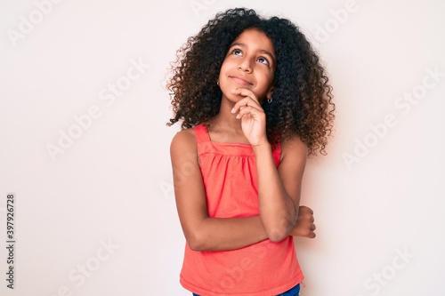 African american child with curly hair wearing casual clothes thinking concentrated about doubt with finger on chin and looking up wondering
