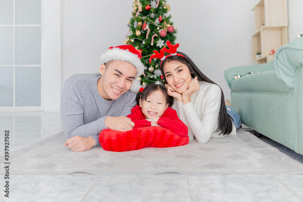 Fototapeta premium asian children and her mother rest chin on her hands, asian family playing near Christmas tree, they feeling happy and smile, child development and family activity, celebration in Christmas season
