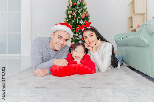 asian children and her mother rest chin on her hands  asian family playing near Christmas tree  they feeling happy and smile  child development and family activity  celebration in Christmas season