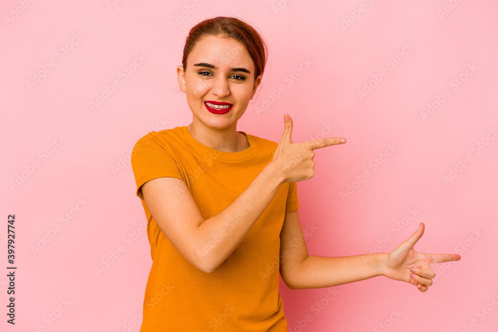 Young arab mixed race woman pointing with forefingers to a copy space, expressing excitement and desire. Young arab mixed race woman pointing with forefingers to a copy space, expressing excitement and desire.