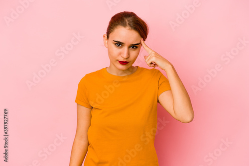 Young arab mixed race woman pointing temple with finger, thinking, focused on a task.