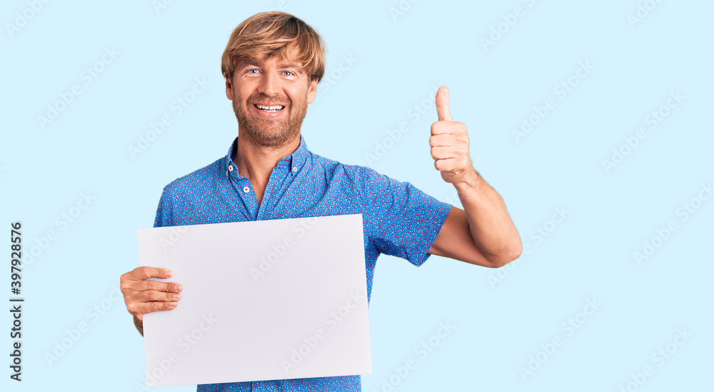 Handsome caucasian man with beard holding sale poster smiling happy and positive, thumb up doing excellent and approval sign Handsome caucasian man with beard holding sale poster smiling happy and positive, thumb up doing excellent and approval sign