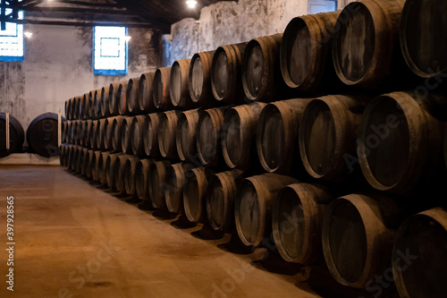 Old porto lodge with rows of oak wooden casks for slow aging of fortified ruby or tawny porto wine in Vila Nova de Gaia, Portugal