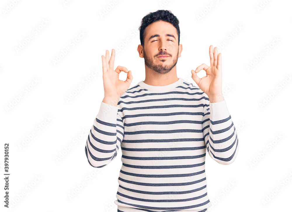 Young hispanic man wearing casual clothes relaxed and smiling with eyes closed doing meditation gesture with fingers. yoga concept. Young hispanic man wearing casual clothes relaxed and smiling with eyes closed doing meditation gesture with fingers. yoga concept.