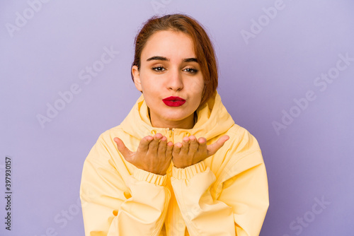 Young arab mixed race woman folding lips and holding palms to send air kiss.