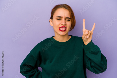 Young arab mixed race woman showing rock gesture with fingers